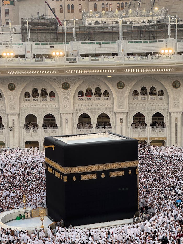 Aerial view of the Kaaba in Mecca, Saudi Arabia, surrounded by a large crowd of pilgrims.